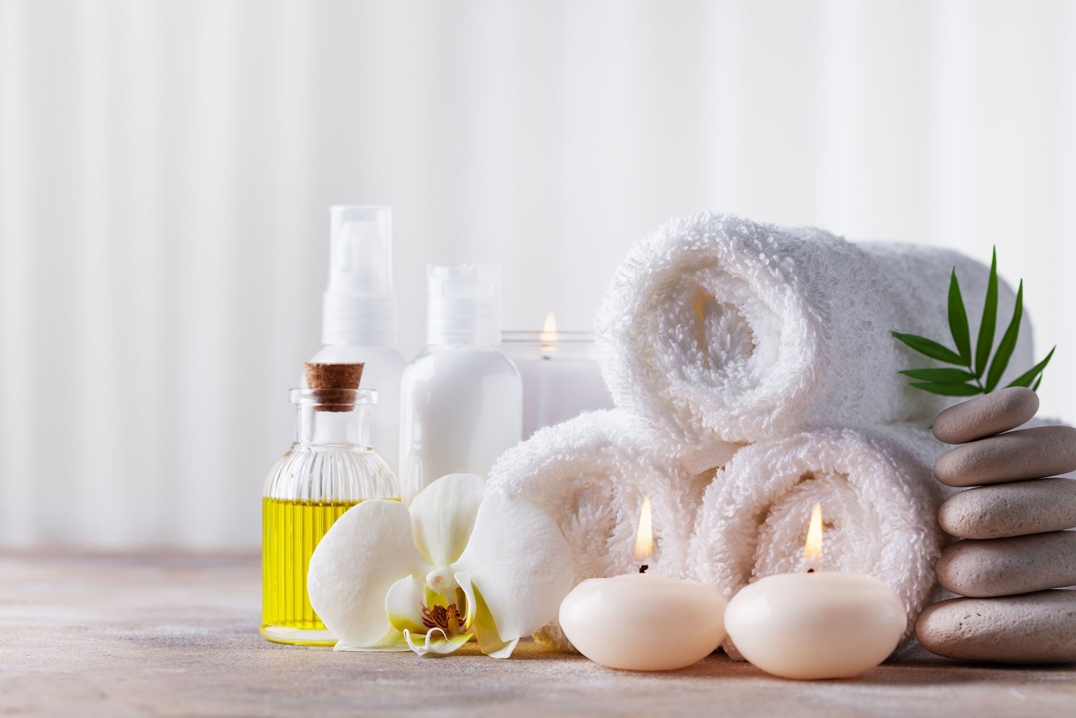 Massage pebbles, orchid flowers, towels, cosmetic products and burning candles.