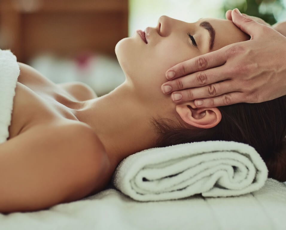 A woman relaxing while receiving a head massage.