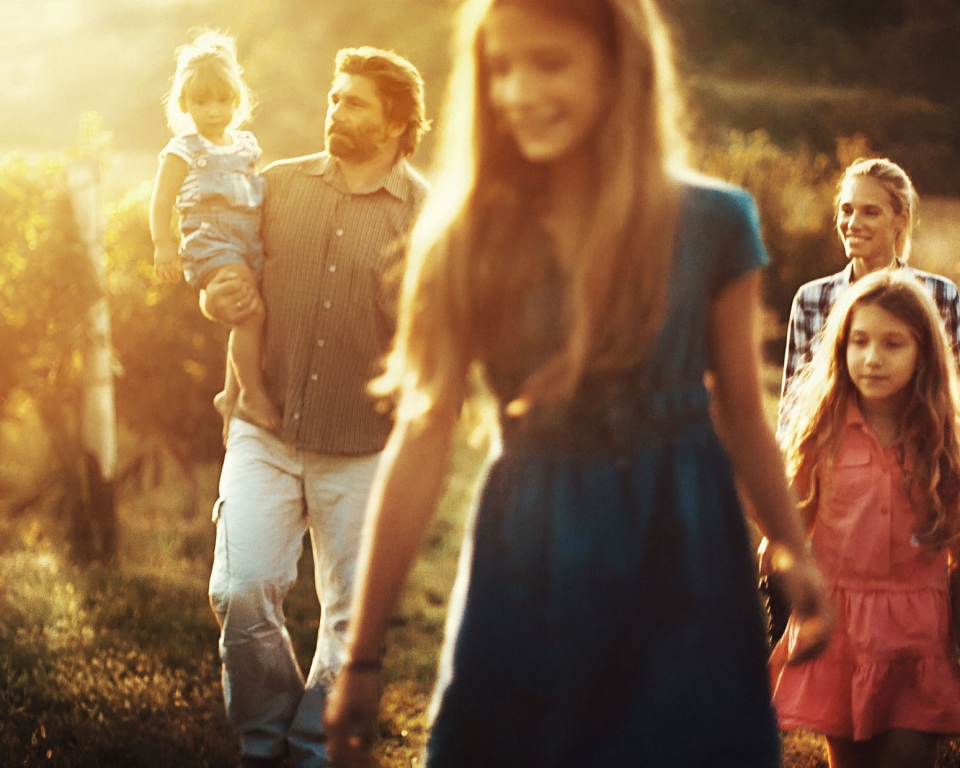 Family with three daughters walking through their vineyard on a late summer afternoon