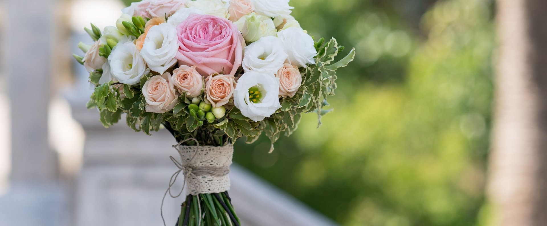 a bridal bouquet of roses, freesia, eustoma standing on a stone background