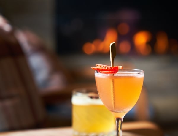 Two colorful cocktails served on a wooden tabletop.