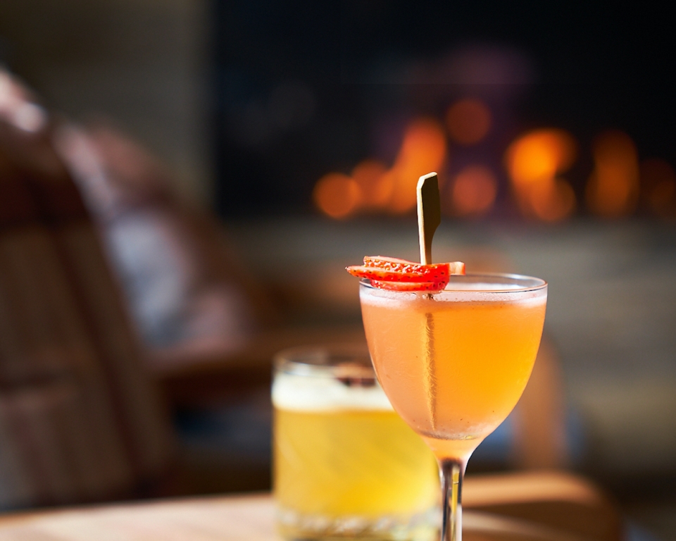 Two colorful cocktails served on a wooden tabletop.