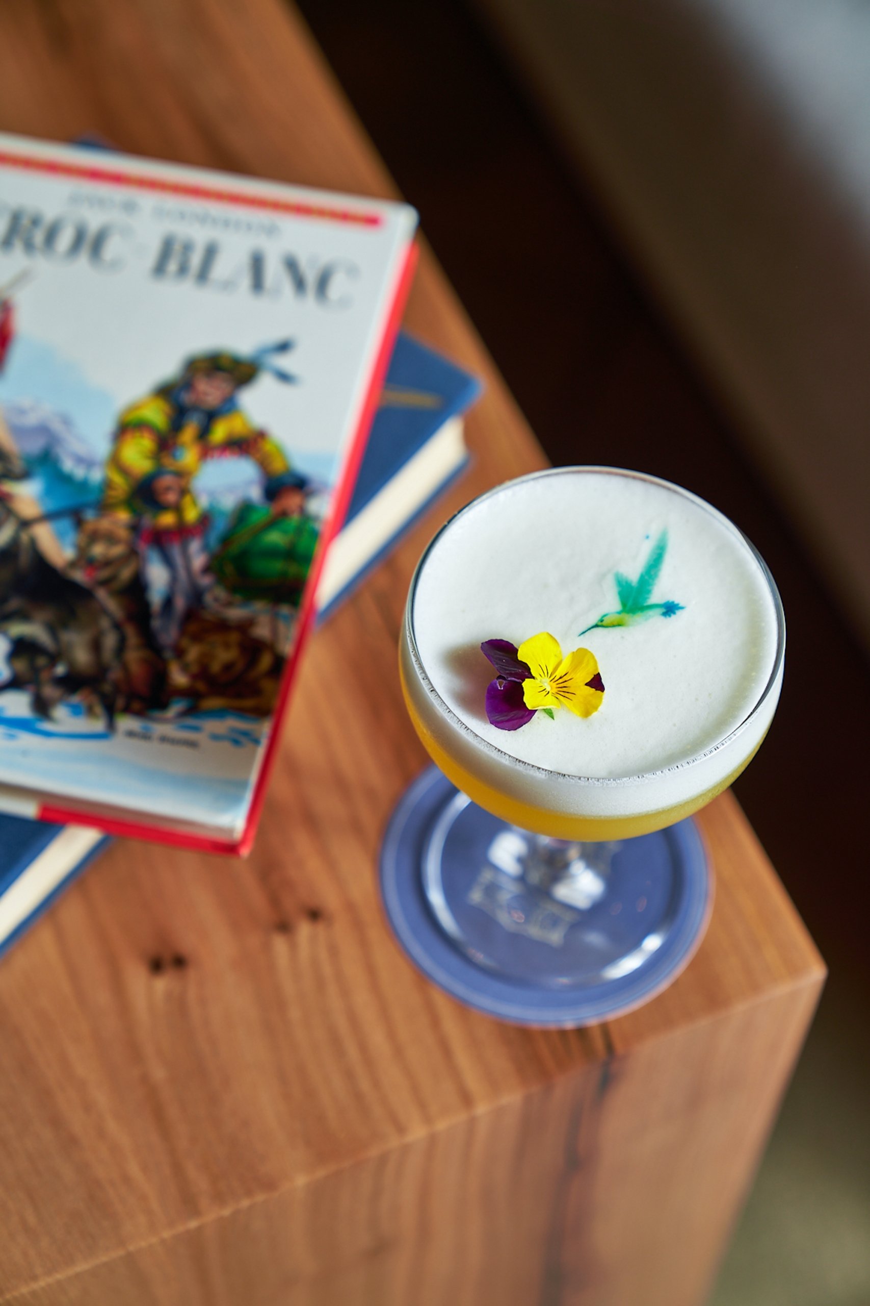 A cocktail served with yellow and purple flower garnishes.