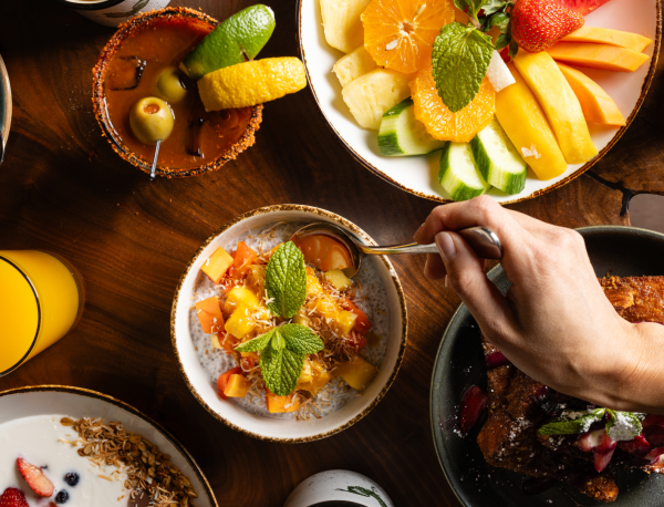 Benicia's Kitchen tablescape of breakfast dishes featuring yogurt parfait, fruit platter, chia pudding, and french toast.