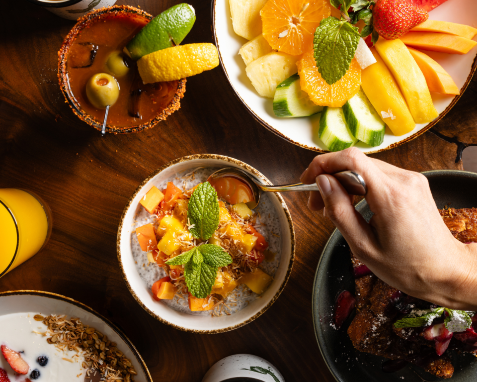 Benicia's Kitchen tablescape of breakfast dishes featuring yogurt parfait, fruit platter, chia pudding, and french toast.