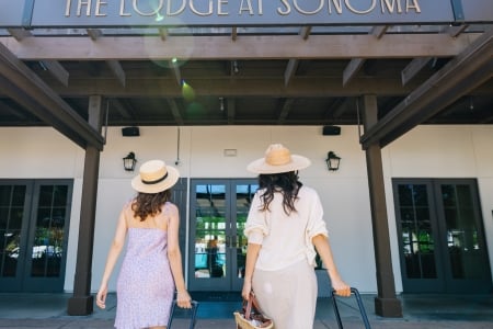 Two women with suitcases walking into The Lodge at Sonoma