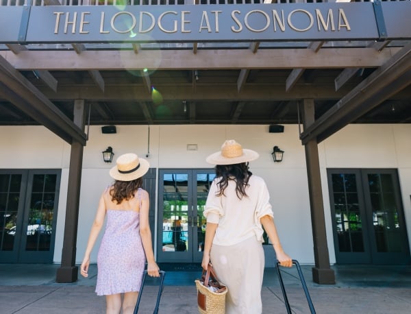Two women with suitcases walking into The Lodge at Sonoma