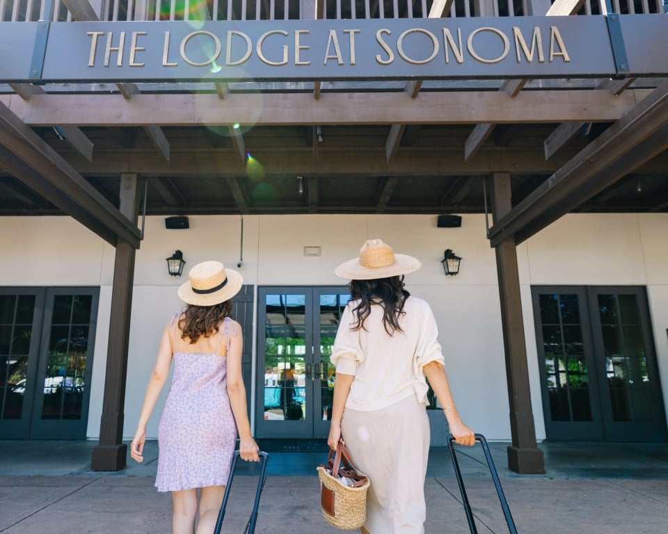 Two women with suitcases walking into The Lodge at Sonoma