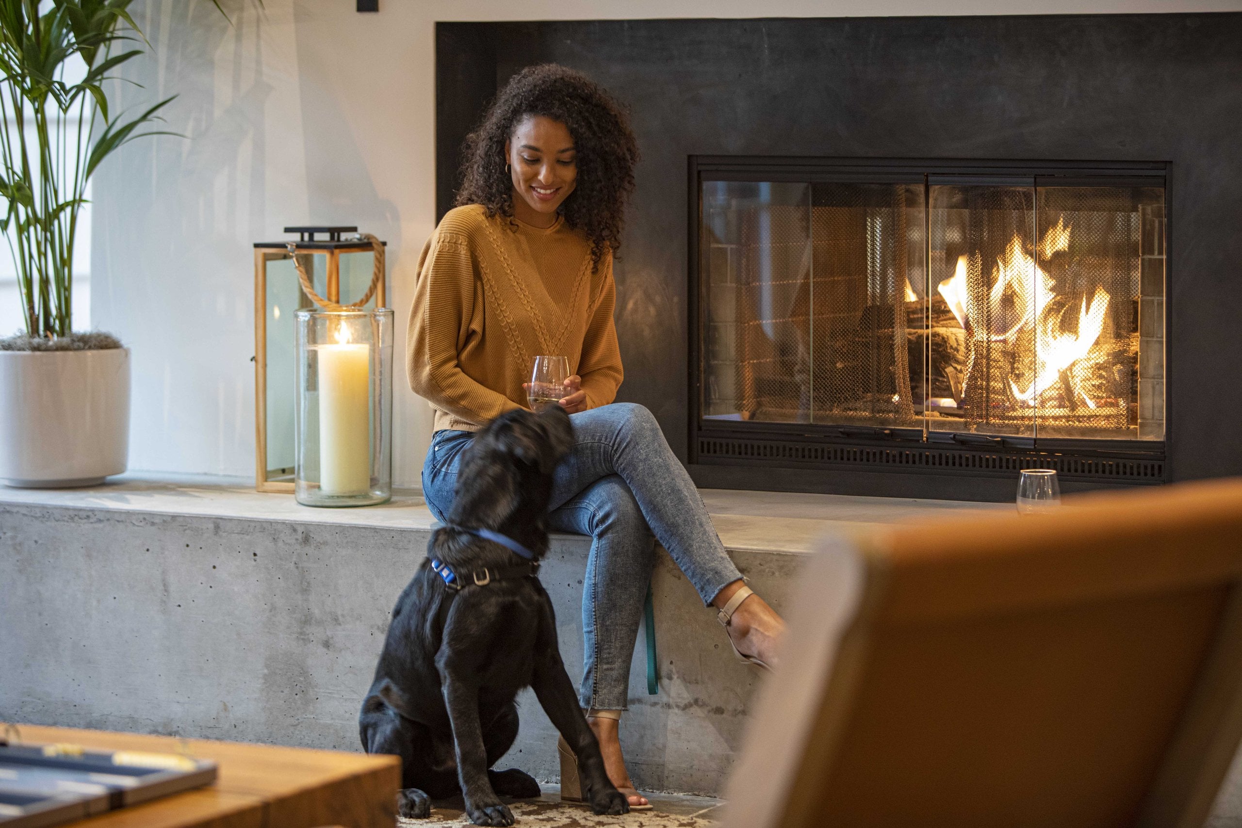 A woman and her dog relax by the fireplace in the lobby at The Lodge at Sonoma