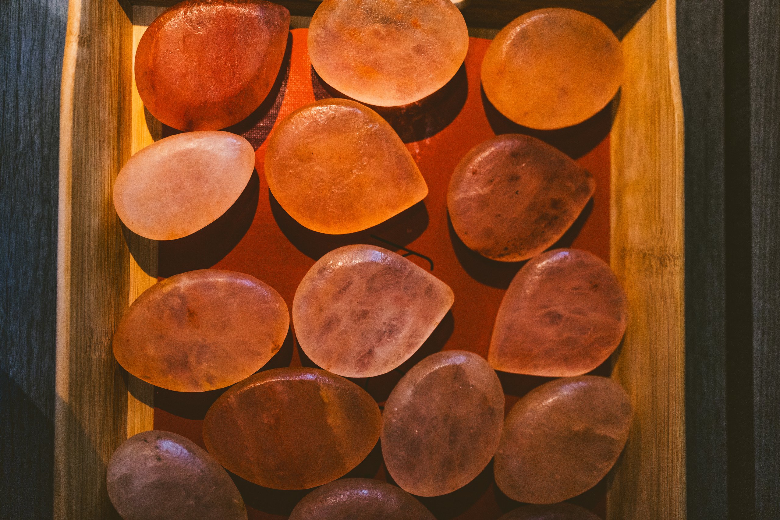 Warmly lit Himalayan salt stones in a wooden tray at The Spa at the Lodge